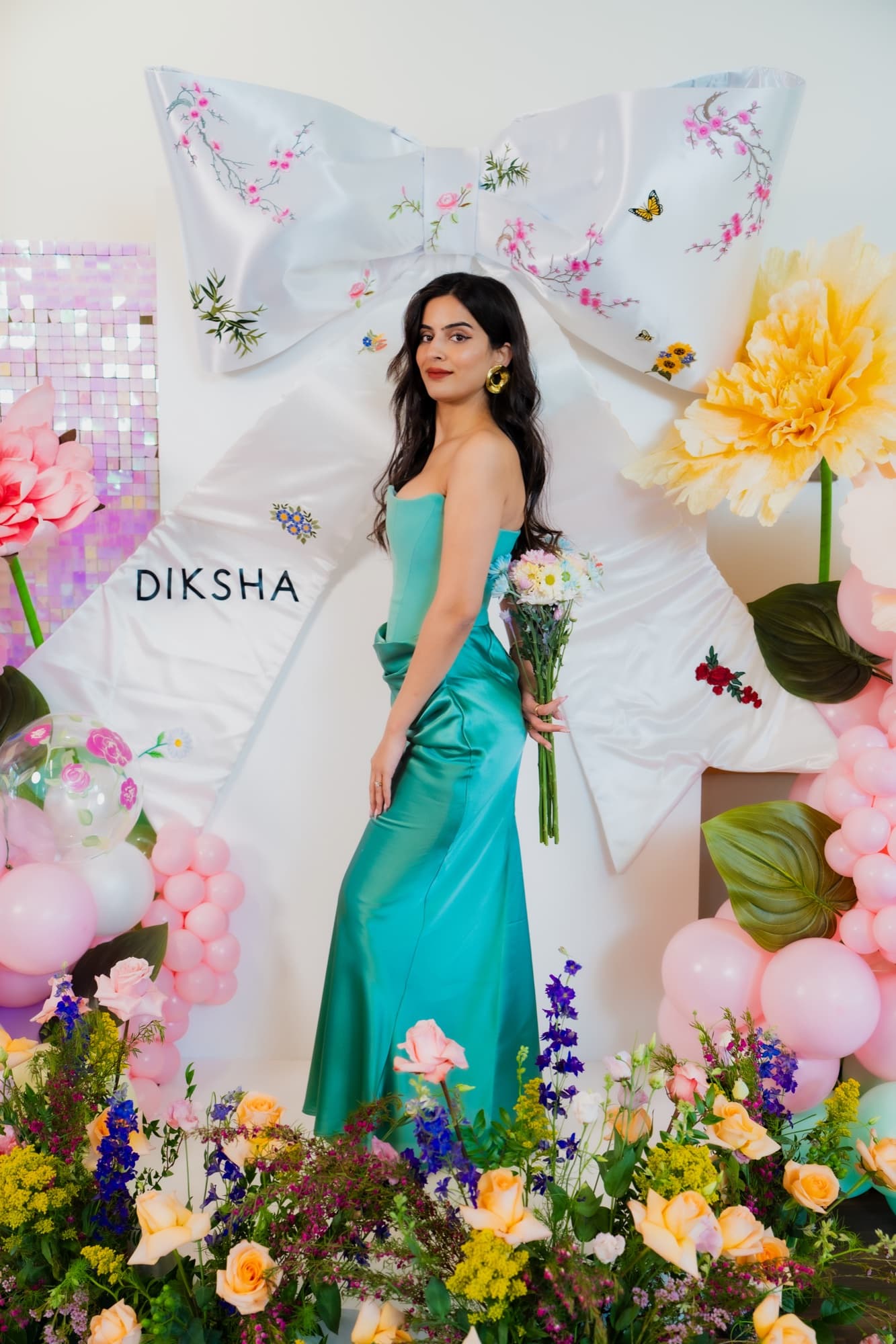 A colorful floral celebration installation with a guest standing within the finished design.