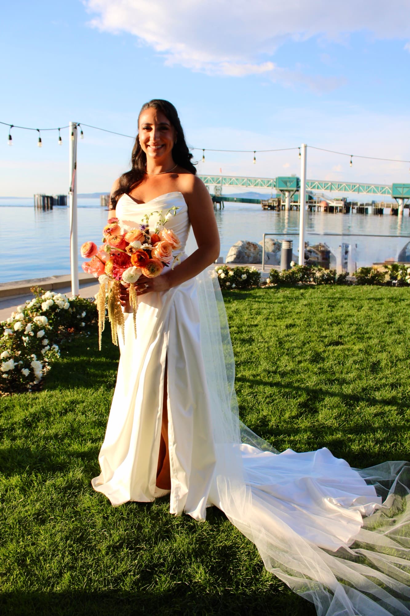 A bride holding a warm-toned bouquet within an outdoor wedding setting.