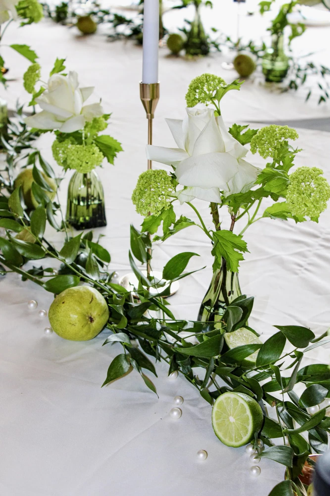 A green-and-citrus wedding tablescape detail with candles and glassware.